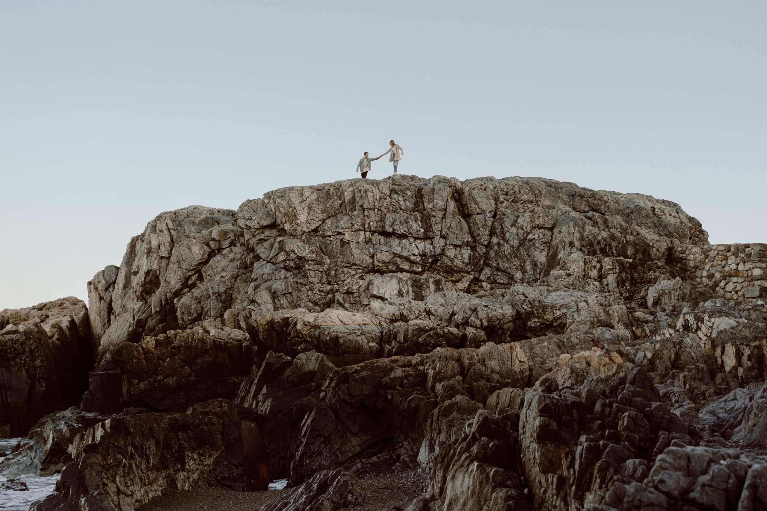 Engaged couple holds hands as they hike along the summit of Castle Rock in Marblehead, MA, capturing their adventure and love in this scenic location