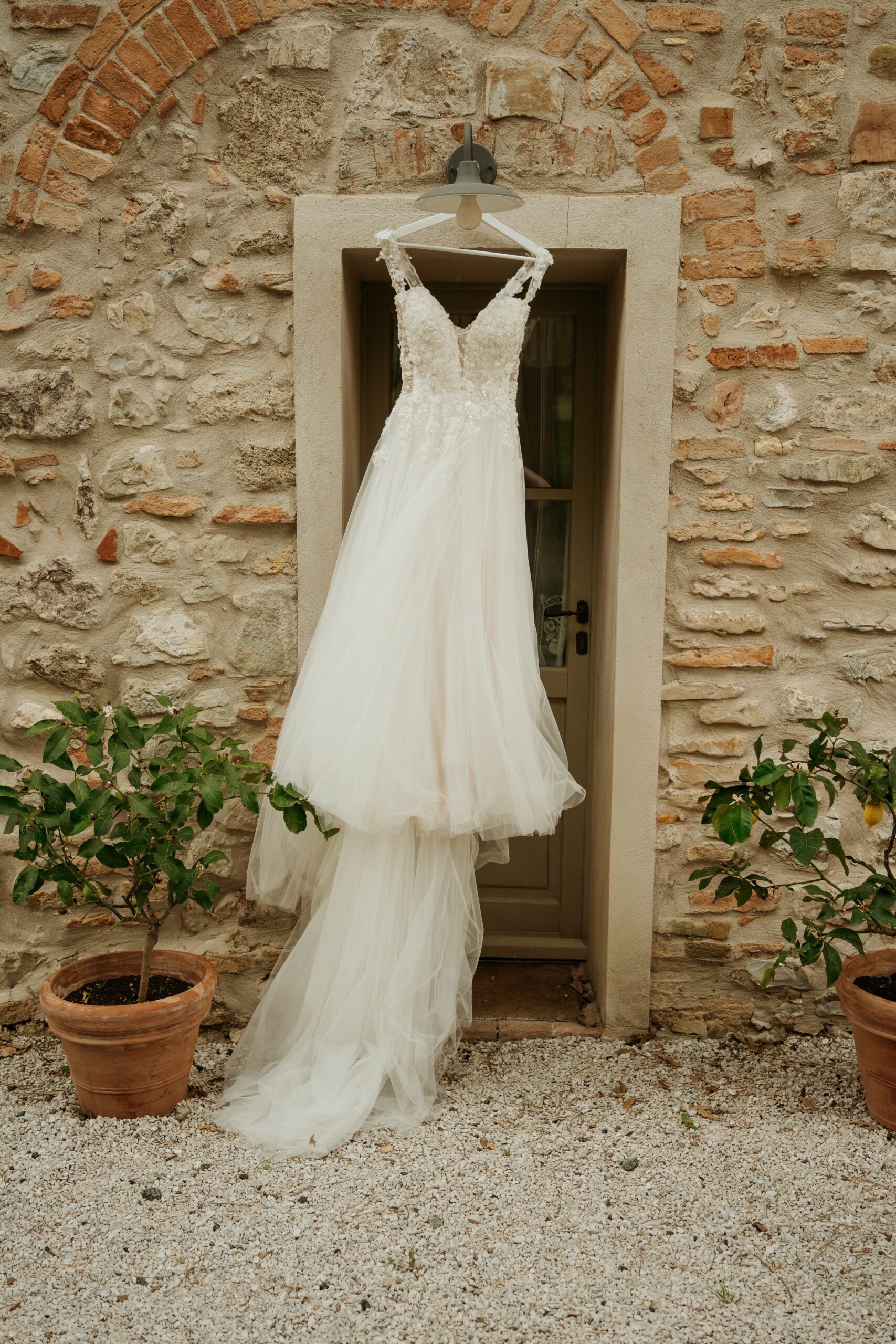 Lacey Plunging neckline wedding dress hung outside of an Italian Villa Wedding Venue in Tuscany blowing in the wind