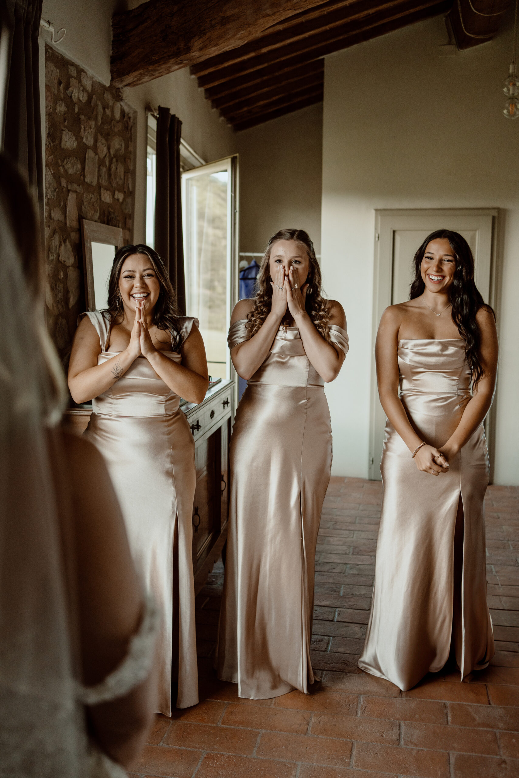 Emotional first look with bride and her bridesmaids that are wearing champagne bridesmaids dresses of different styles.