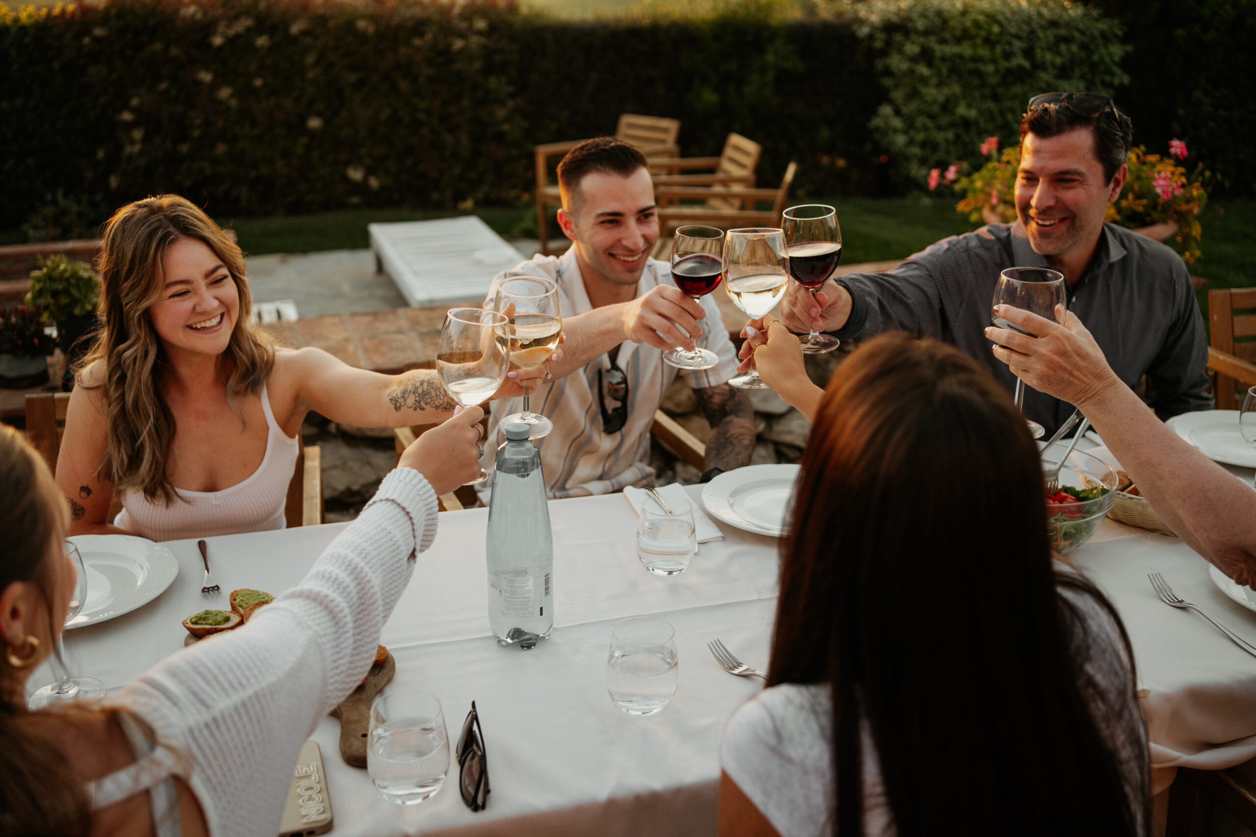 Bride, groom, and their guests cheer their glasses of wine during the Tuscan Wedding Welcome Dinner