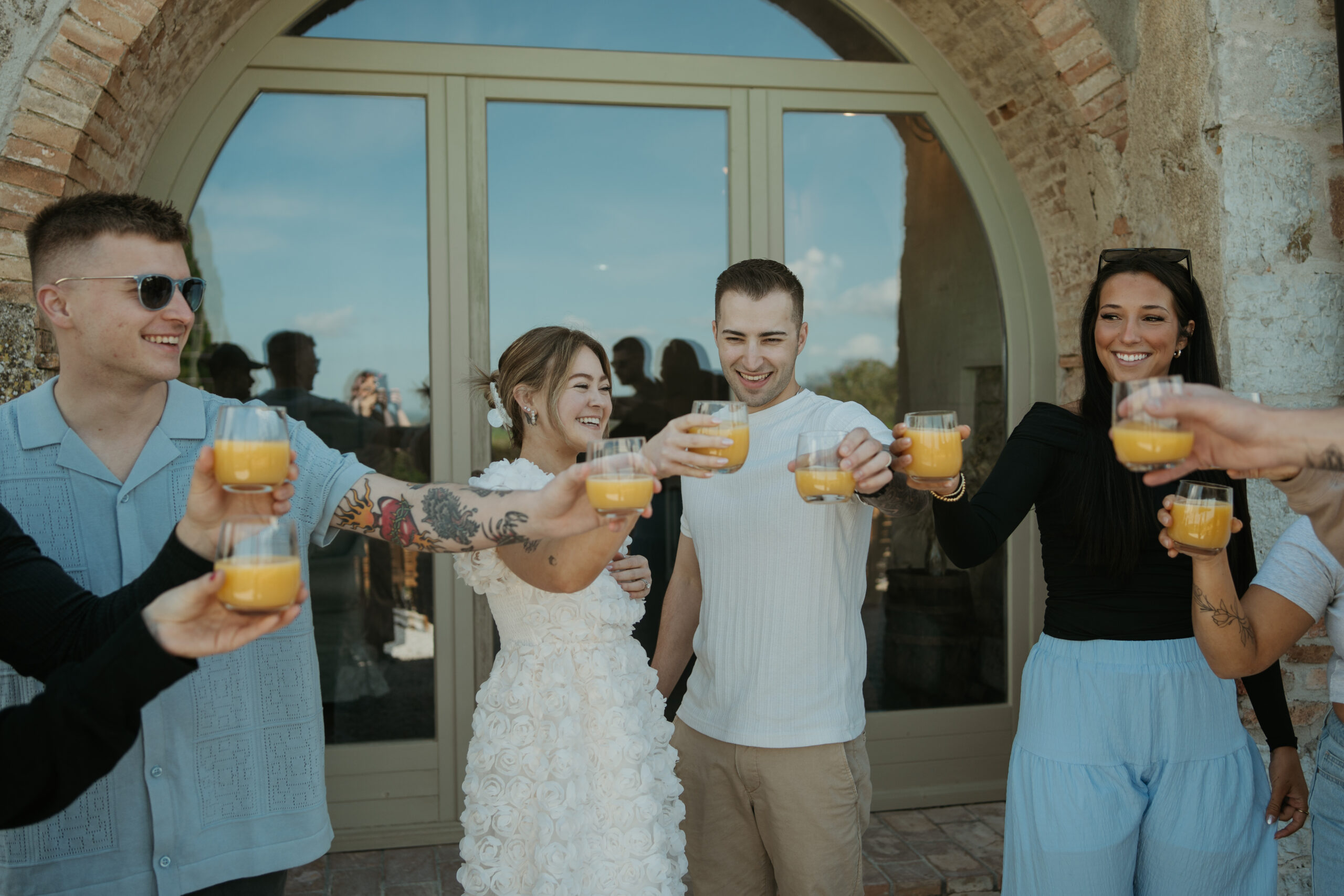 Bride and groom cheer mimosas with their friends outside their Italian Villa Wedding Venue in Volterra