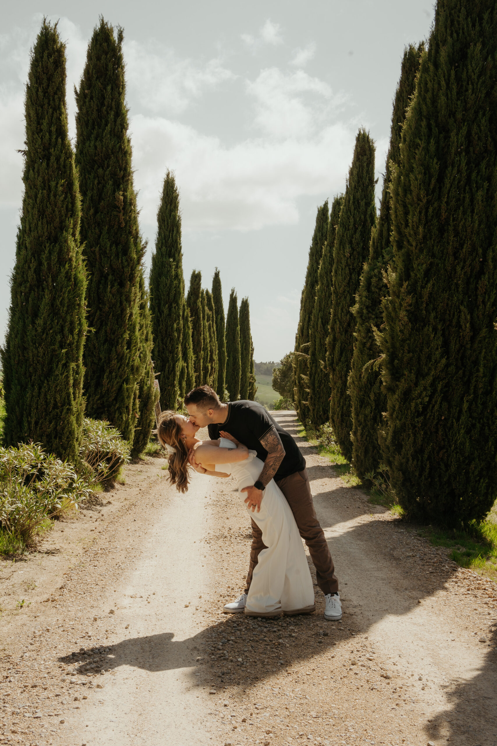 Bride and groom share a romantic dip kiss in the middle of rows of Tuscan Pines during their Italy destination wedding excursion