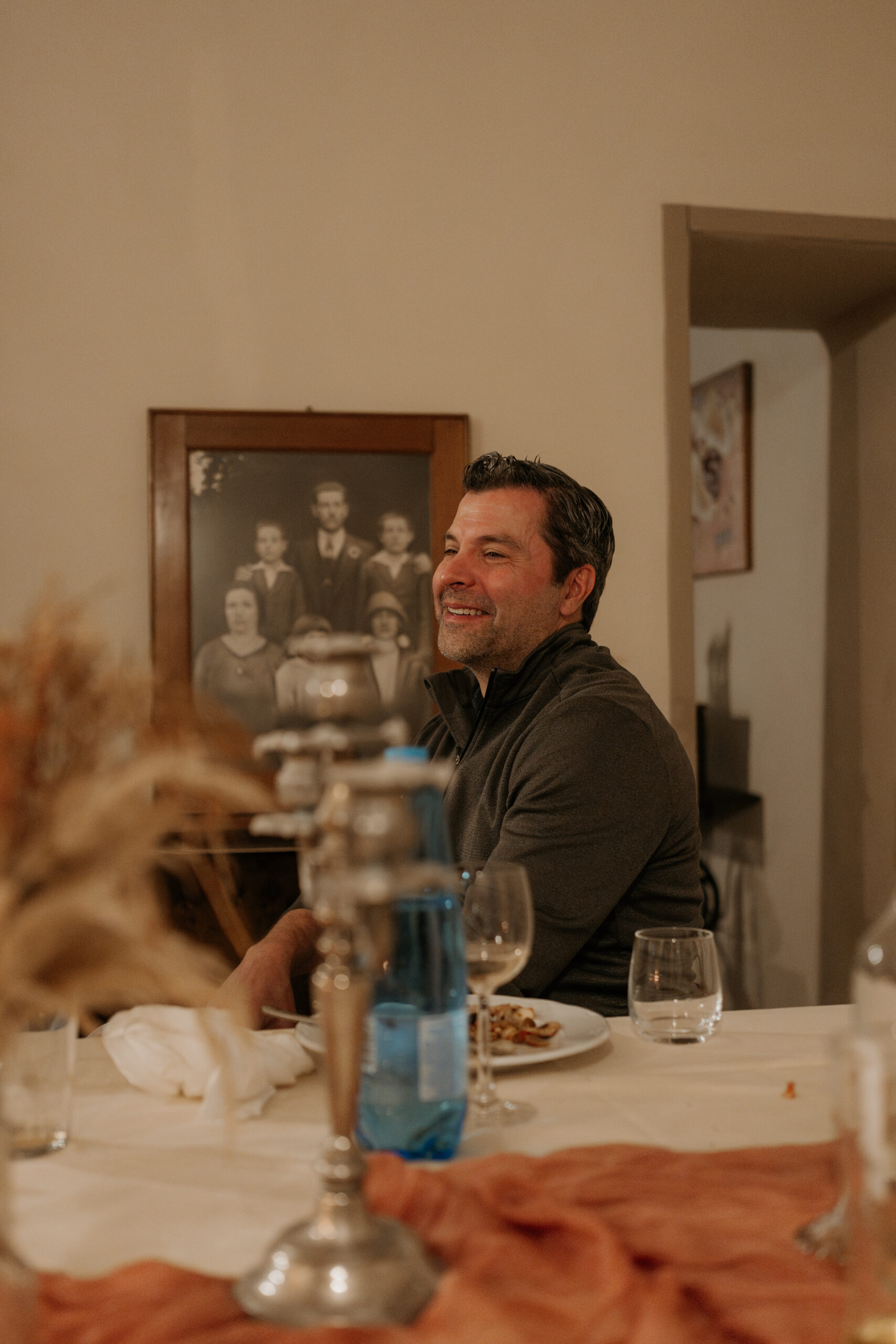 Father of groom laughs while at the table during the Tuscan destination wedding candle litrehearsal dinner