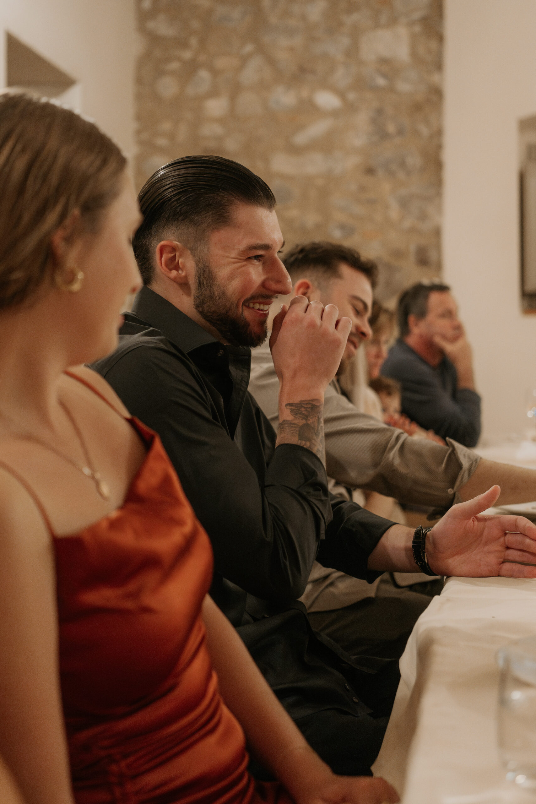 Best man laughs while at the table during the Tuscan destination wedding candle lit rehearsal dinner