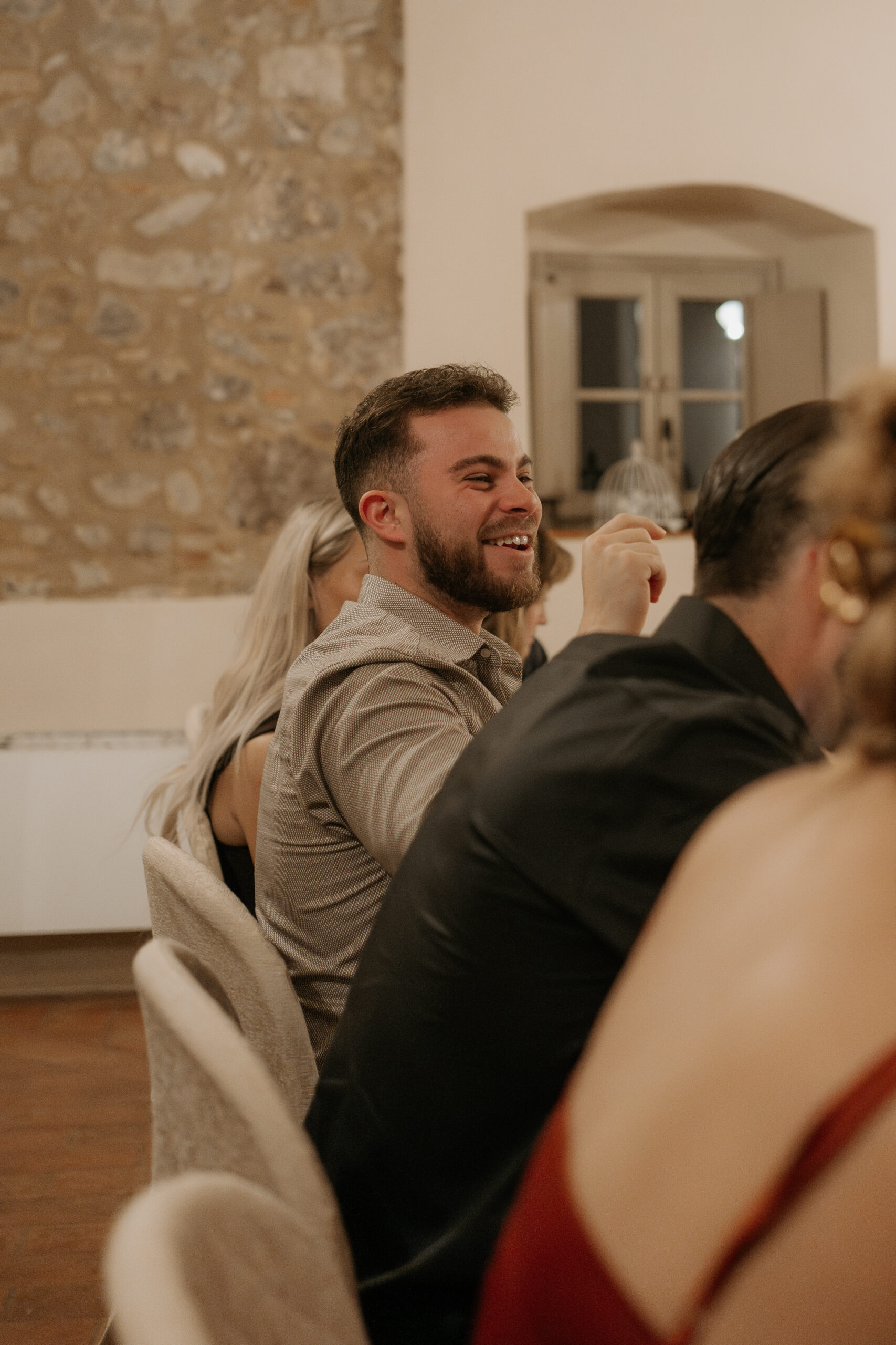Groomsmen laughs while at the table during the Tuscan destination wedding candle lit rehearsal dinner