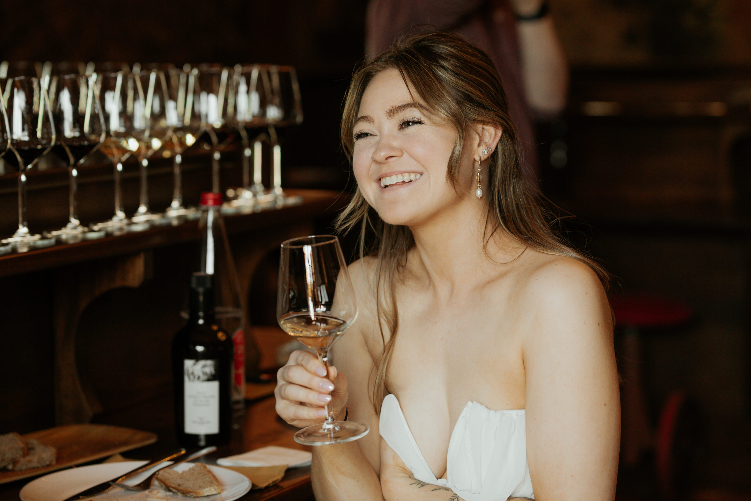A happy bride to be as she smiles off in the distance while holding a glass of white wine during a wine tasting at MonteRosola in Volterra. 